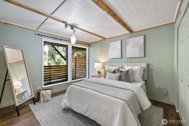 bedroom with baseboards, dark wood-style floors, and beam ceiling