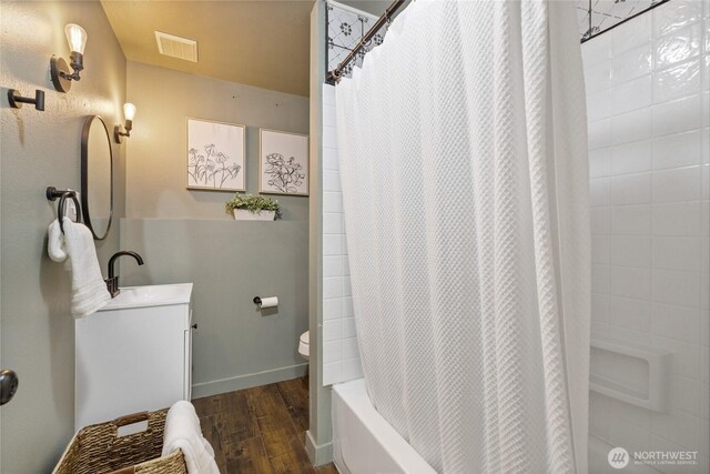 bathroom with visible vents, shower / bath combo with shower curtain, vanity, wood finished floors, and baseboards