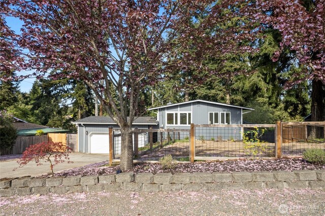mid-century home with a garage, concrete driveway, and fence private yard
