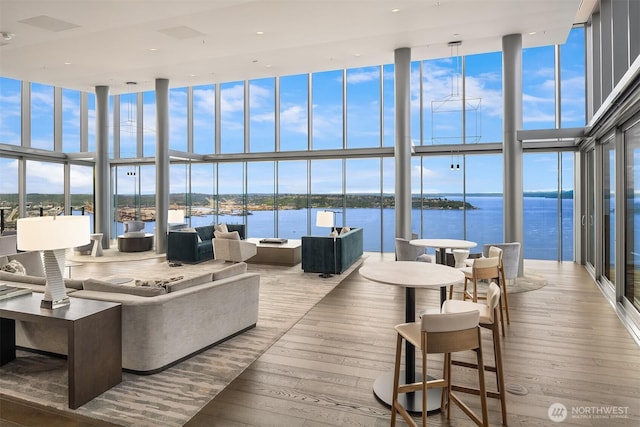 121 Stewart St Unit 905, Seattle, WA 98121 - living room with a wall of windows, hardwood / wood-style flooring, a towering ceiling, and a water view