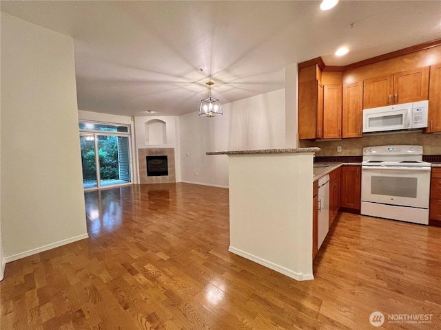 kitchen with decorative backsplash, white appliances, light wood-type flooring, baseboards, and open floor plan