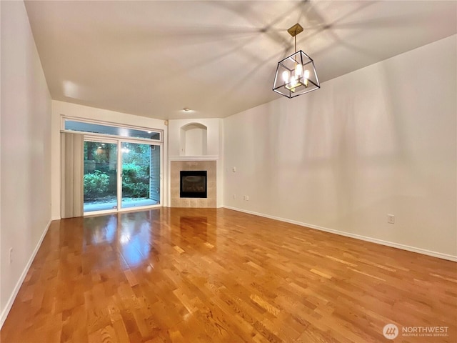 unfurnished living room with baseboards, wood finished floors, and a tiled fireplace