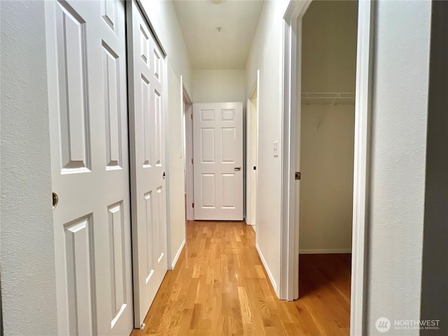 corridor with light wood-style flooring and baseboards