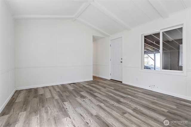 unfurnished room with baseboards, vaulted ceiling with beams, and wood finished floors