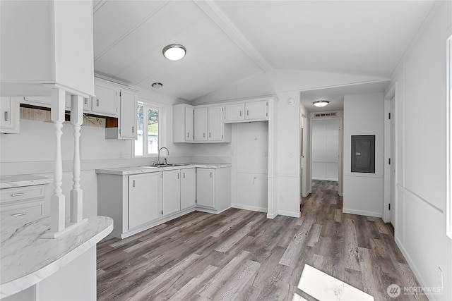 kitchen featuring electric panel, a sink, wood finished floors, light countertops, and vaulted ceiling with beams
