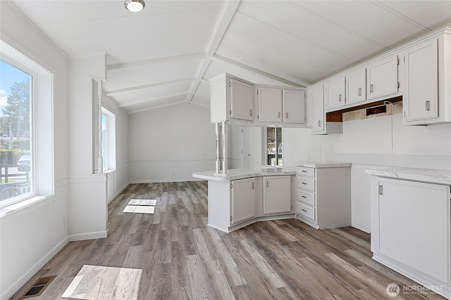 kitchen featuring light wood finished floors, lofted ceiling with beams, light countertops, and white cabinets