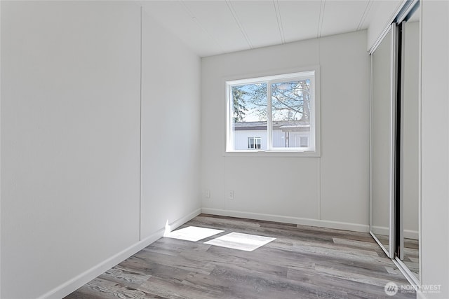 unfurnished bedroom featuring baseboards, a closet, and wood finished floors