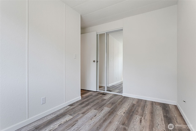 unfurnished room with baseboards, visible vents, and wood finished floors