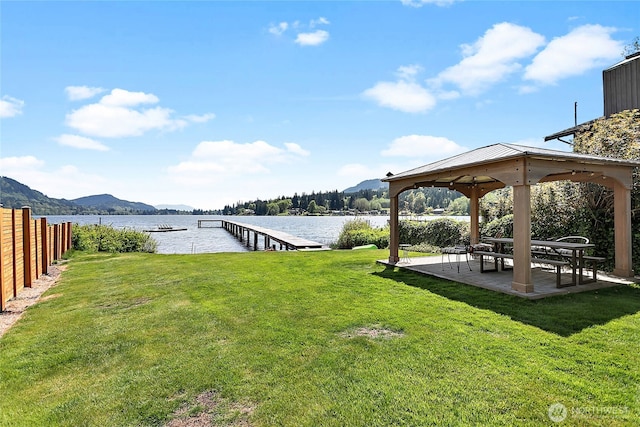view of yard featuring a water and mountain view, a gazebo, fence, and a dock