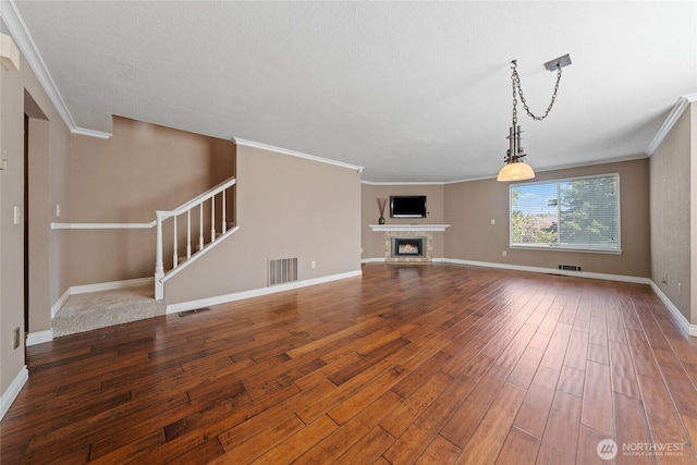 unfurnished living room featuring crown molding, baseboards, visible vents, and hardwood / wood-style floors