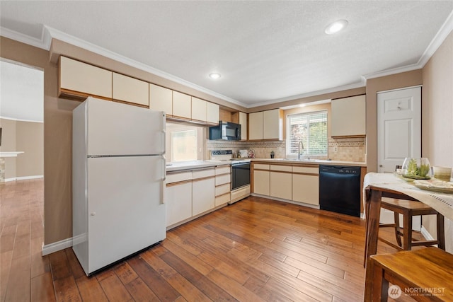 kitchen with crown molding, light countertops, hardwood / wood-style floors, tasteful backsplash, and black appliances