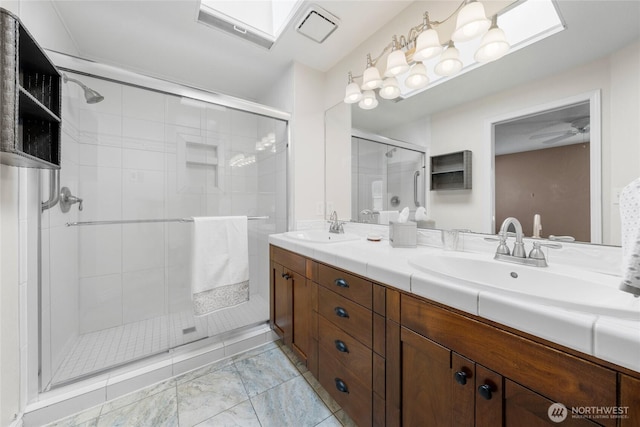 bathroom featuring double vanity, visible vents, a shower stall, and a sink