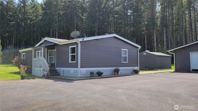 151 W Nikula Rd, Winlock, WA 98596 - manufactured / mobile home with a storage shed, a view of trees, and an outbuilding