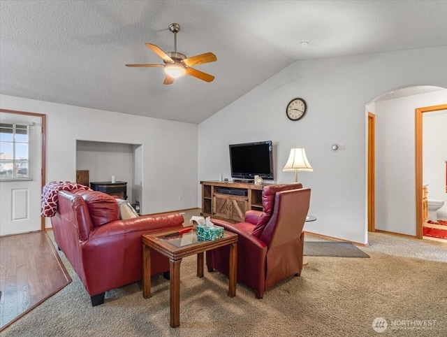 living area featuring carpet flooring, arched walkways, ceiling fan, and lofted ceiling