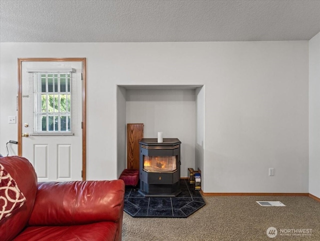 carpeted living area featuring a wood stove, a textured ceiling, and baseboards