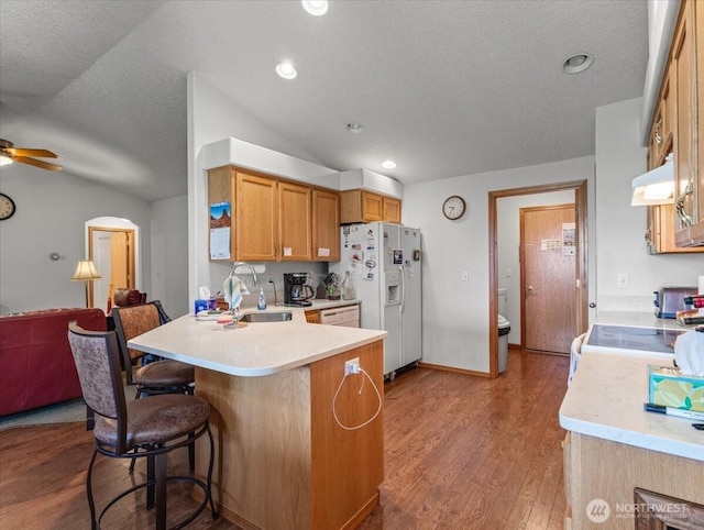 kitchen featuring white appliances, a peninsula, light countertops, and a sink