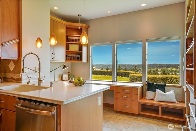 kitchen featuring brown cabinetry, decorative light fixtures, dishwasher, a sink, and light tile patterned floors