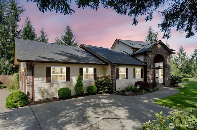 view of front of home featuring brick siding, fence, and a shingled roof