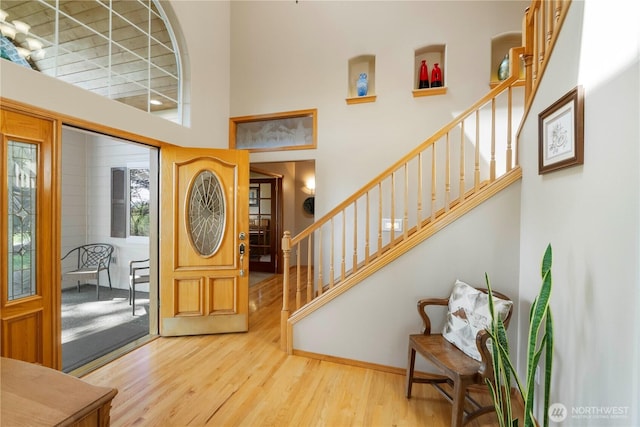 foyer featuring wood finished floors, a high ceiling, and stairway