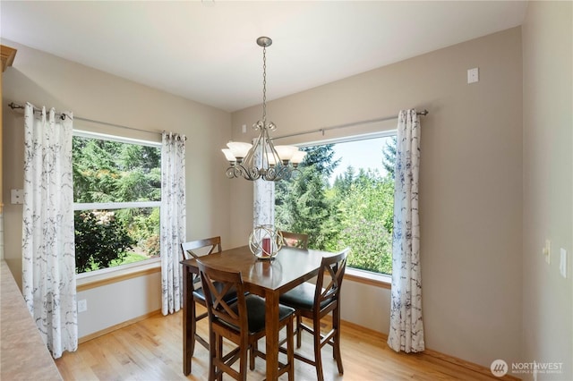 dining area with baseboards, a notable chandelier, a healthy amount of sunlight, and light wood-style floors