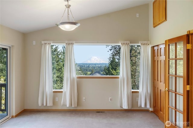 unfurnished room with plenty of natural light, light carpet, and lofted ceiling