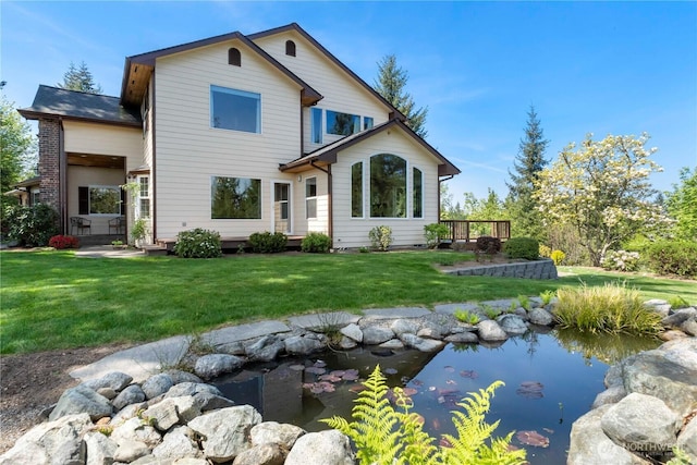 rear view of property with a lawn and a garden pond