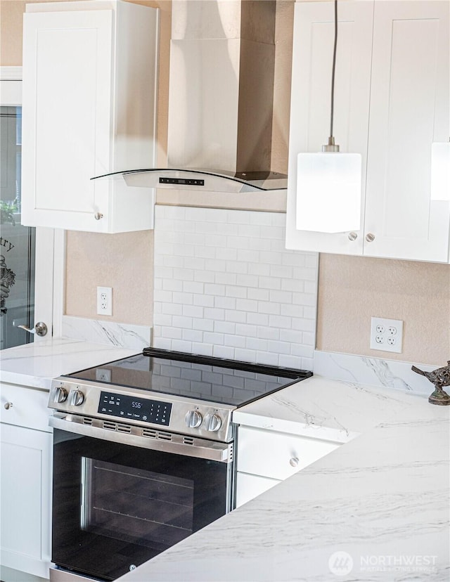 kitchen featuring stainless steel electric range, white cabinetry, tasteful backsplash, and wall chimney exhaust hood