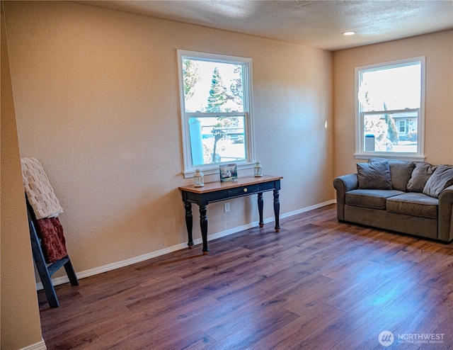sitting room with a textured ceiling, wood finished floors, a textured wall, and baseboards