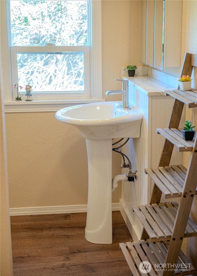 bathroom featuring baseboards, wood finished floors, and a textured wall