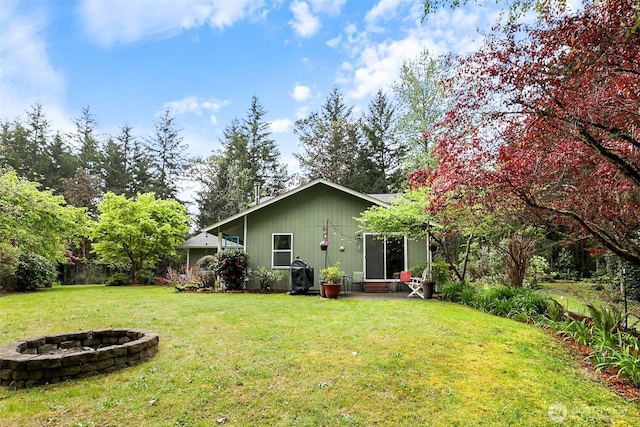 rear view of property featuring a lawn and a fire pit