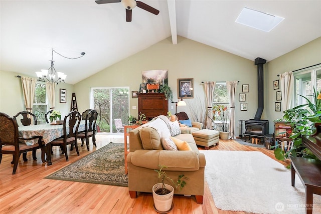 living room featuring a chandelier, a wood stove, light wood finished floors, and ceiling fan