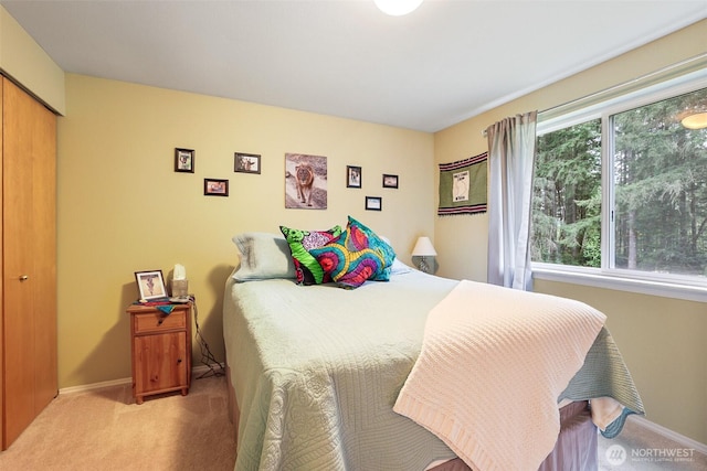 bedroom with light colored carpet, baseboards, and a closet