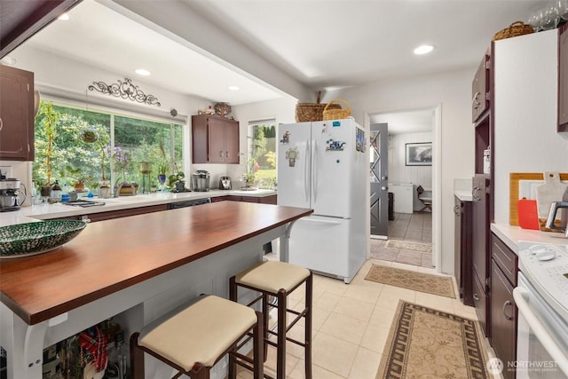 330 15th St, Snohomish, WA 98290 - kitchen featuring white appliances, a kitchen bar, recessed lighting, light tile patterned flooring, and dark brown cabinets