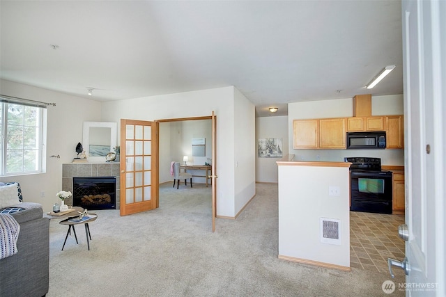 kitchen featuring a tile fireplace, open floor plan, visible vents, black appliances, and light carpet