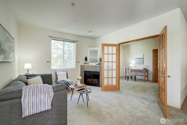 living area with light colored carpet, french doors, and a tiled fireplace