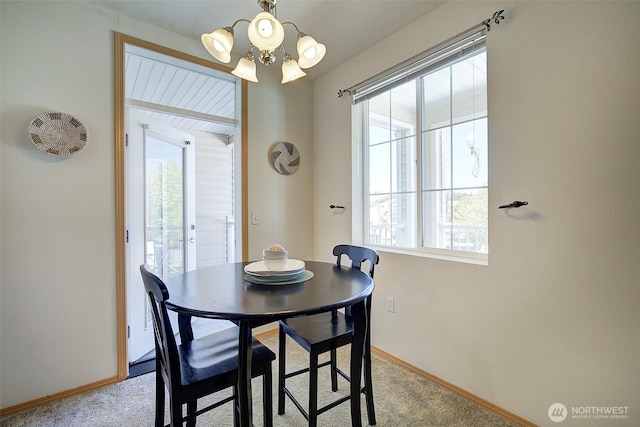 dining area with baseboards, light carpet, and a notable chandelier