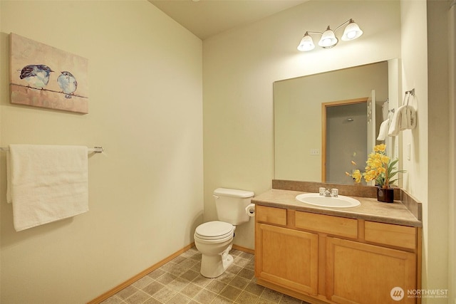 bathroom with toilet, baseboards, and vanity