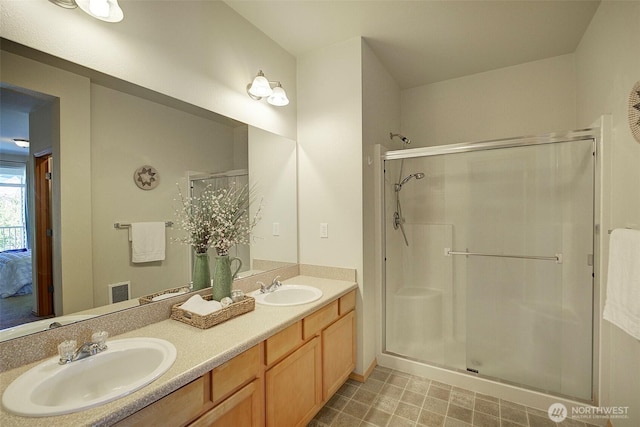 full bathroom with a sink, double vanity, and a shower stall