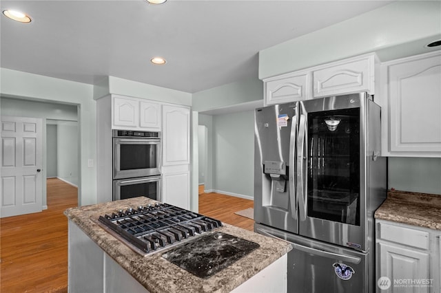 kitchen with recessed lighting, stainless steel appliances, light wood-style floors, white cabinetry, and a center island