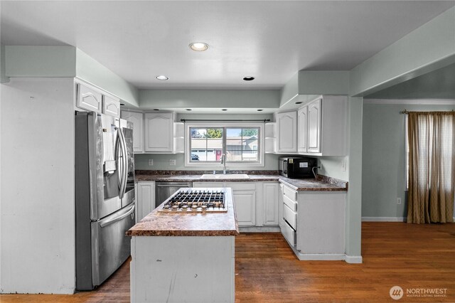 kitchen featuring a sink, a center island, white cabinetry, dark countertops, and appliances with stainless steel finishes