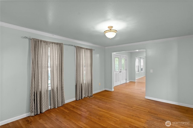spare room with crown molding, wood finished floors, and baseboards