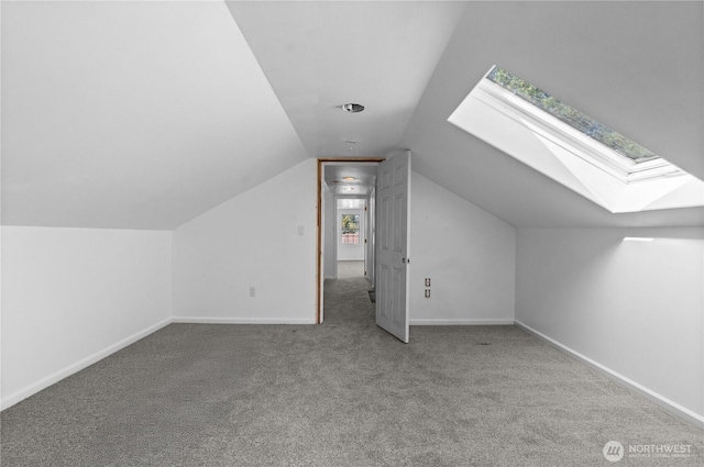 bonus room with baseboards, vaulted ceiling with skylight, and carpet flooring