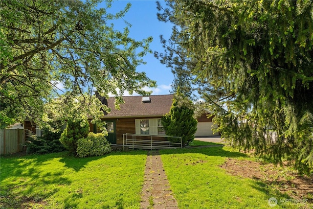 rear view of house with a garage, fence, and a yard