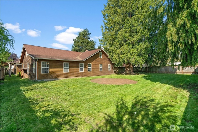 rear view of house with a fenced backyard and a lawn