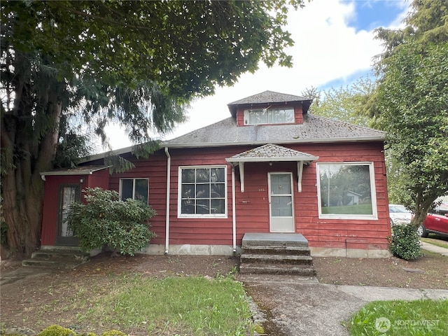 bungalow with entry steps and a shingled roof