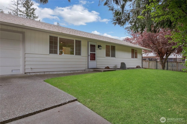 view of front of property featuring a front lawn, roof with shingles, fence, and concrete driveway