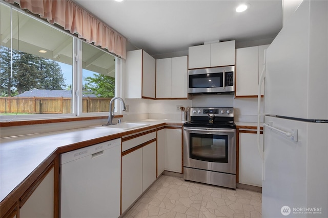 kitchen with a sink, light countertops, white cabinets, light tile patterned floors, and stainless steel appliances