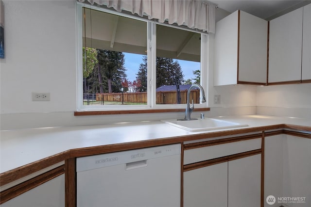 kitchen featuring a sink, dishwasher, white cabinets, and light countertops