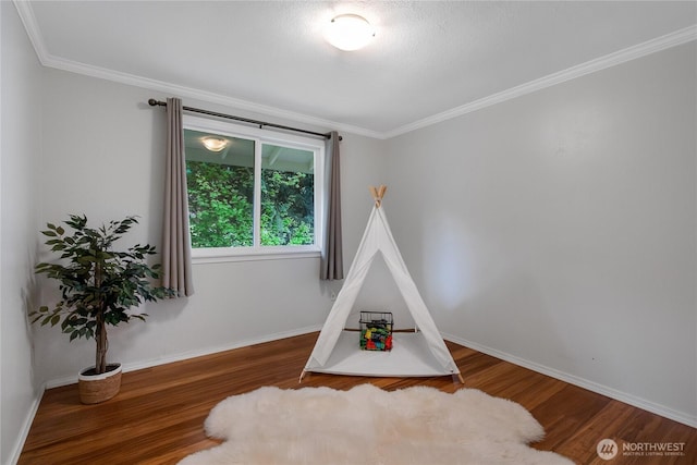 rec room featuring baseboards, ornamental molding, and wood finished floors