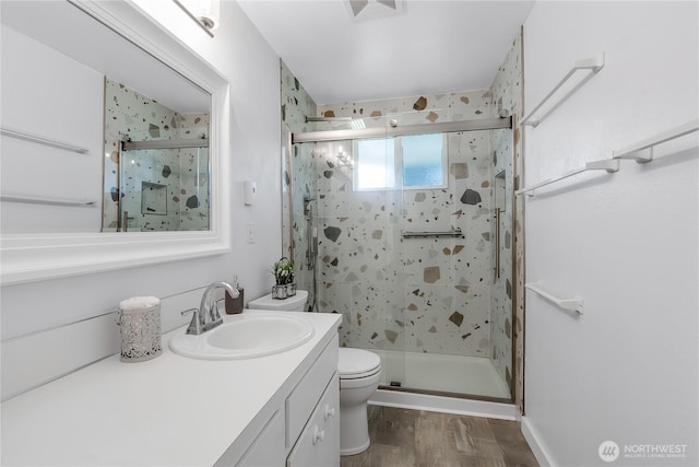 bathroom with toilet, a stall shower, wood finished floors, and vanity